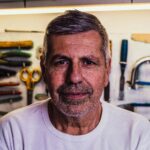 Portrait of a senior man with tools in the background, exuding confidence.